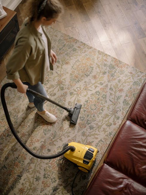 A person is operating a yellow portable air mover on a patterned carpet in an indoor setting, likely during a professional cleaning session by Carpet Cleaning BR1. The carpet appears clean and dry, wi